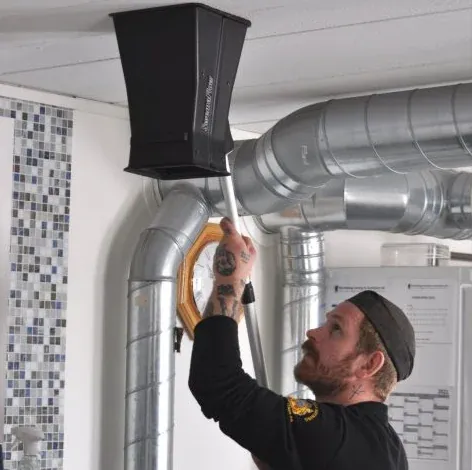 Sotare mäter luftflödet vid en ventilationskanal i taket